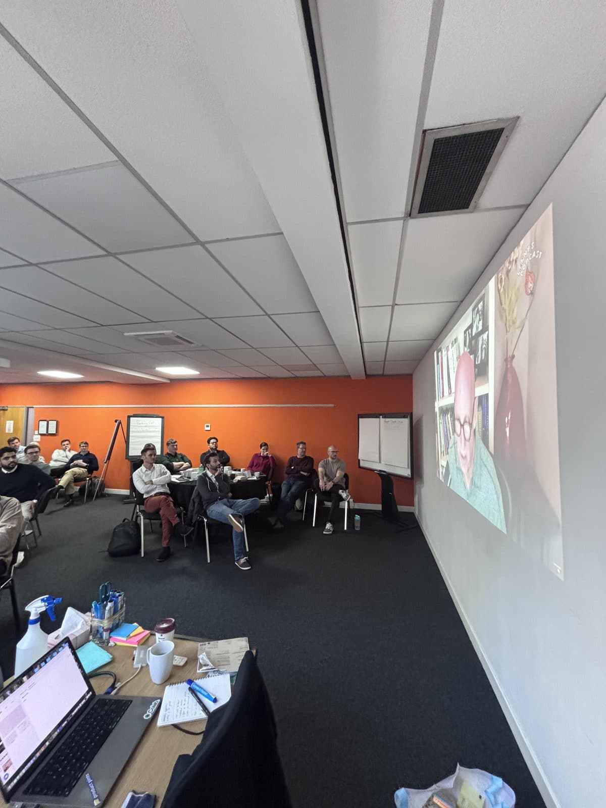 A live session with the team in the room and a speaker joining remotely on screen.