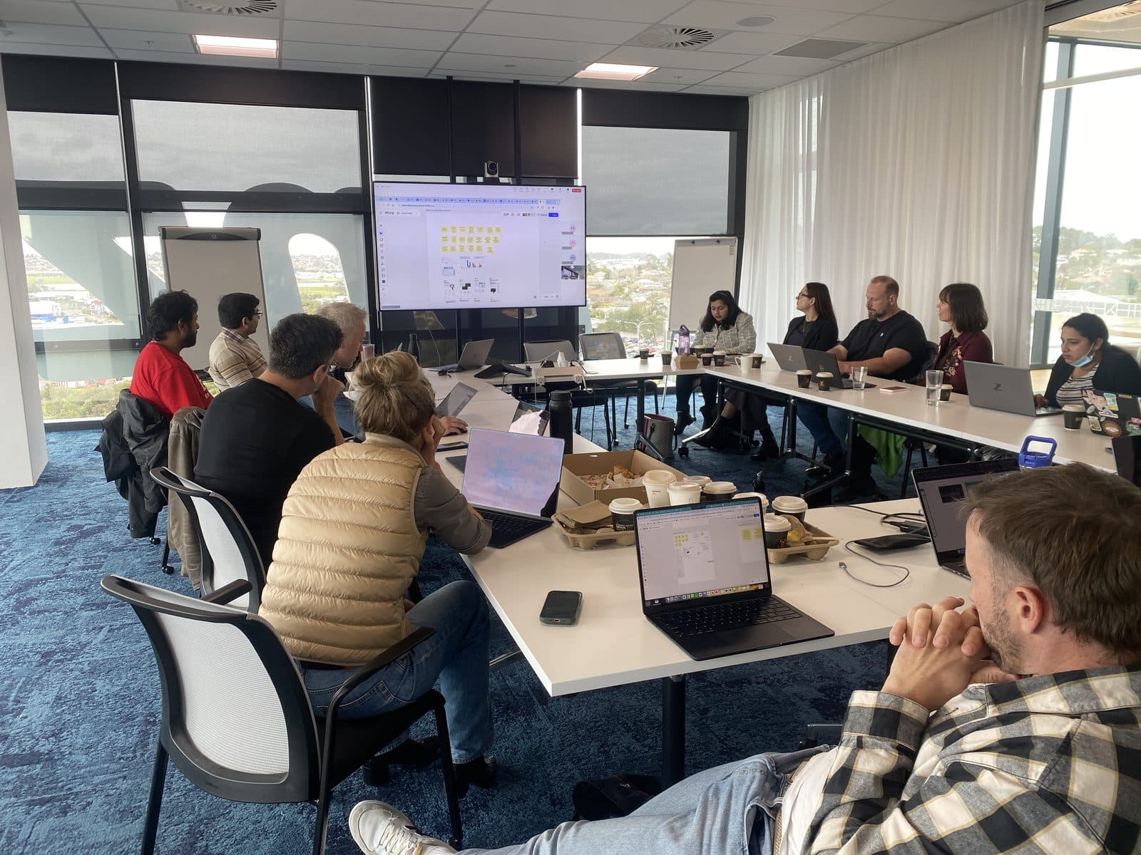 EROAD team mapping an opportunity solution tree in Miro on the big screen during a discovery workshop.