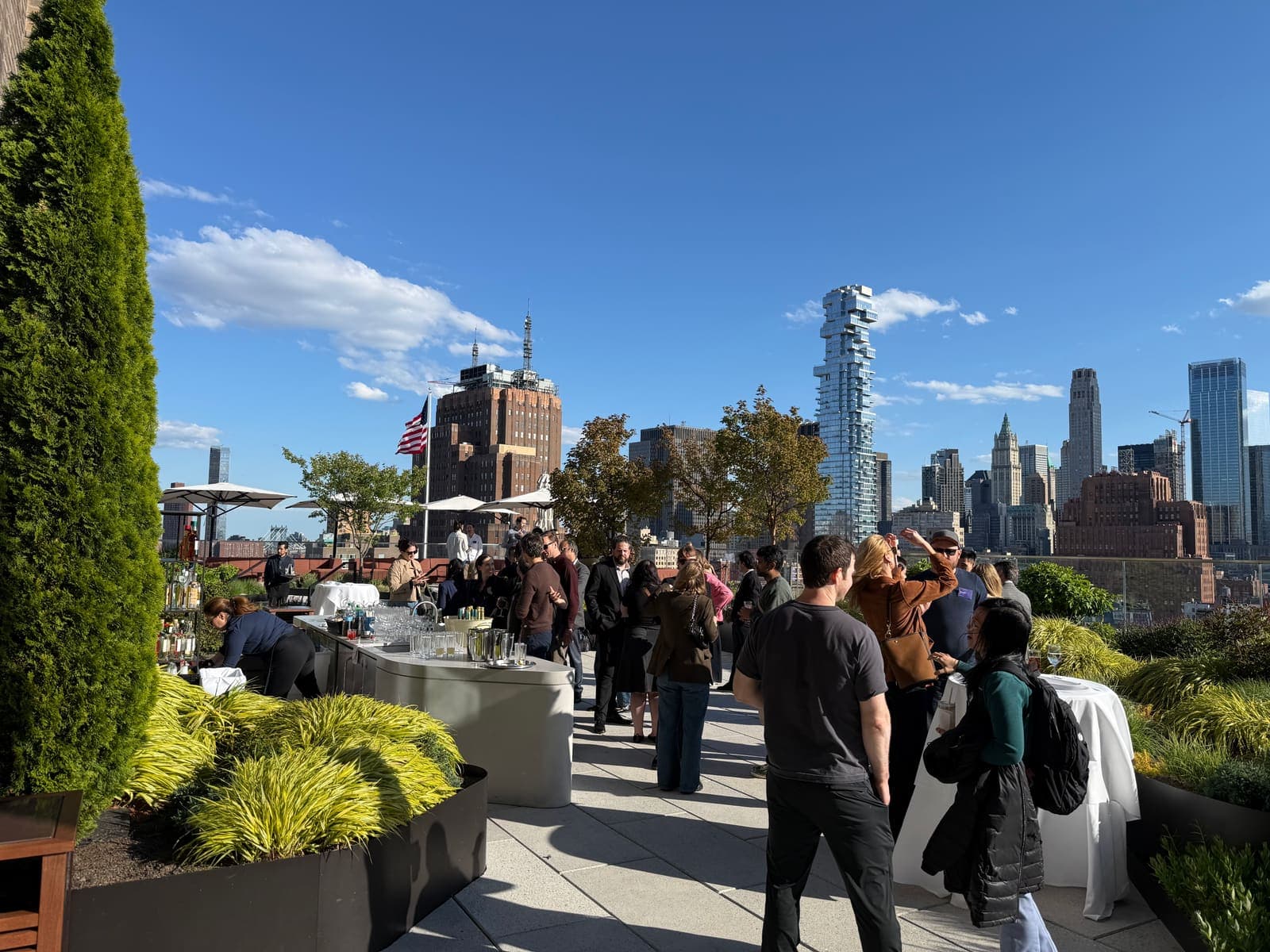 Guests networking on a rooftop overlooking the Lower Manhattan skyline.